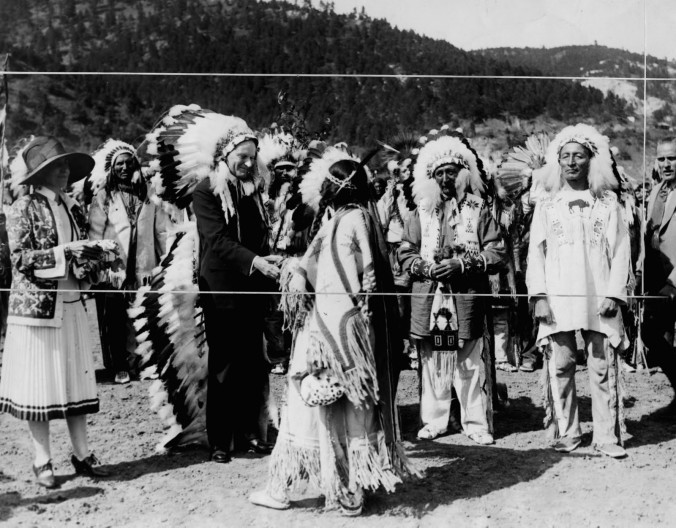 Marked for cropping, this photograph was taken upon President Coolidge's honorary induction into the Sioux, 1927. Dubbed Wamble-To-Ka-Ha (Chief "Leading Eagle"), Coolidge also accepted the ceremonial headdress he is wearing. One of the Sioux chiefs said to Coolidge, "They tell us you are the thirtieth President of this great country, but to us you are our first President." 