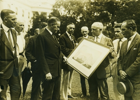 President Coolidge, on the White House grounds, reviews plans for the National Press Building later that same year, September 15, 1925. 