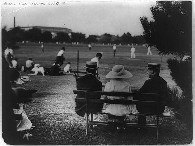 The Coolidges (son John, Grace and Calvin) watch an open field baseball game 