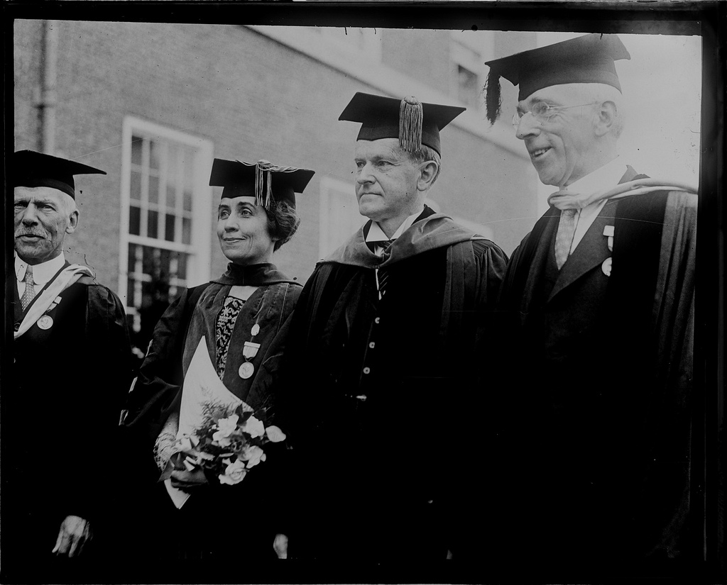 The Coolidges, both college graduates, in cap and gown during their visit to the 150th Anniversary of Phillips Academy. To their right stands the Headmaster, Alfred Stearns, to their left, Alfred L. Ripley (believe it or not). 